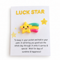 A cute acrylic pin of a smiling yellow star with a rainbow tail, mounted on a white card that reads 'LUCK STAR' with a humorous pocket-holding instruction below.