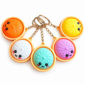 Five colourful kawaii dumpling squishy keychains with smiling faces and metal rings, one assorted colour supplied per order